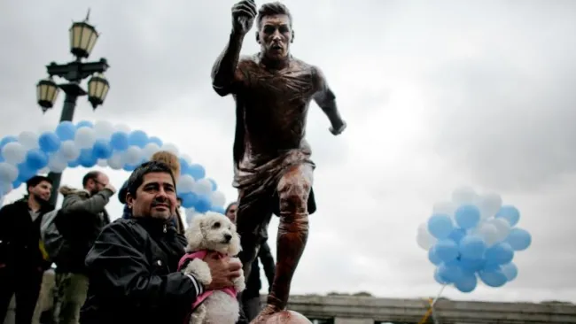 Aficionado argentino posa junto a la estatua de Lionel Messi