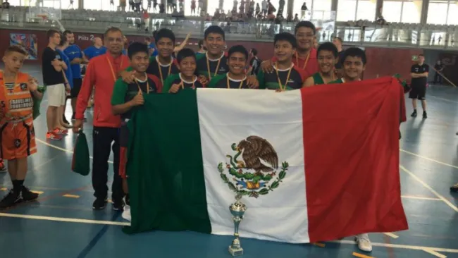 Niños triquis posan con la bandera mexicana y el trofeo de campeón