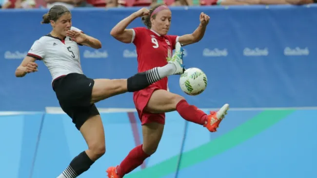 Josee Belanger y Annike Krahn disputan el balón durante el encuentro