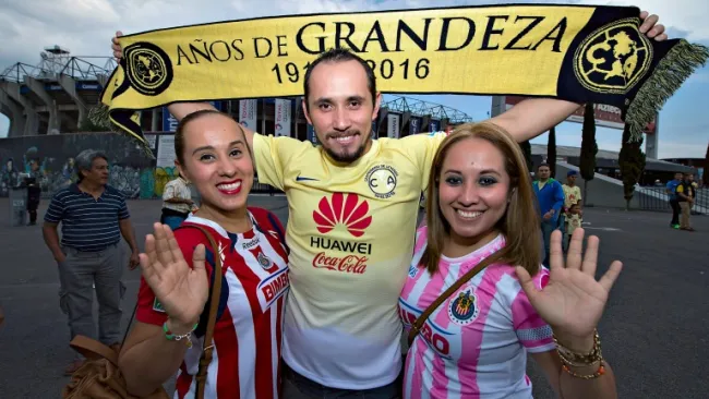 Aficionados posan con una bufanda del América