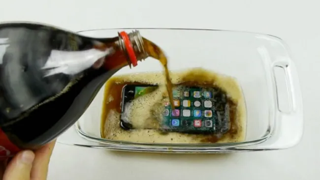 Un iPhone 7 en un refractario con refresco de cola