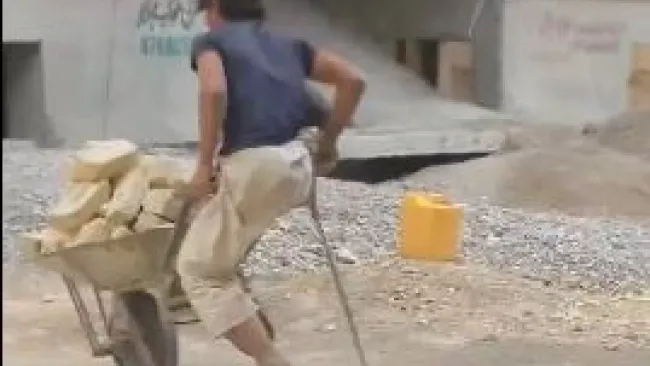 Albañil sin pierna arrastra la carretilla con piedras