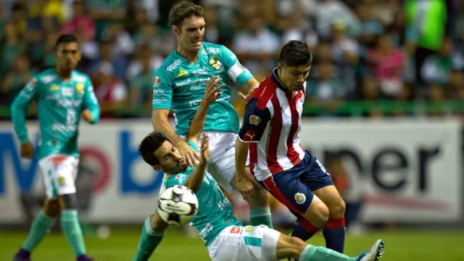 Jugadores del León disputan un balón en el duelo contra Chivas