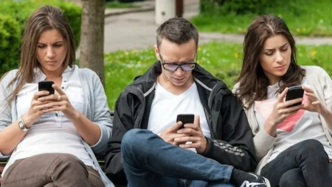 Jóvenes revisando su celular en un parque 