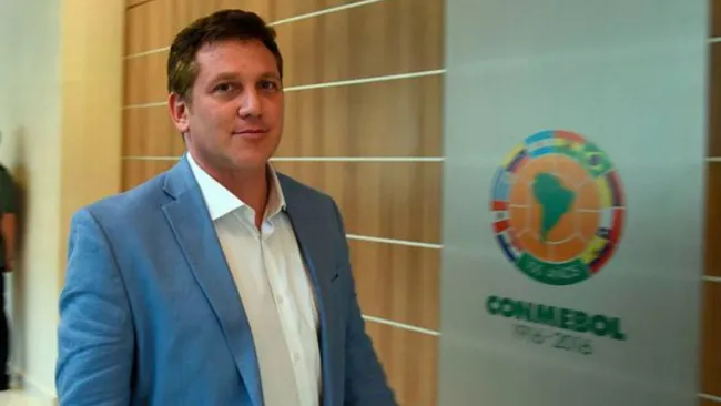 Alejandro Domínguez junto al escudo de Conmebol