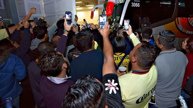 Aficionados del América toman fotos al equipo en su llegada al estadio