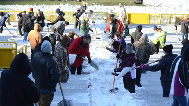Aficionados quitan la nieve de las tribunas del Lambeau Field