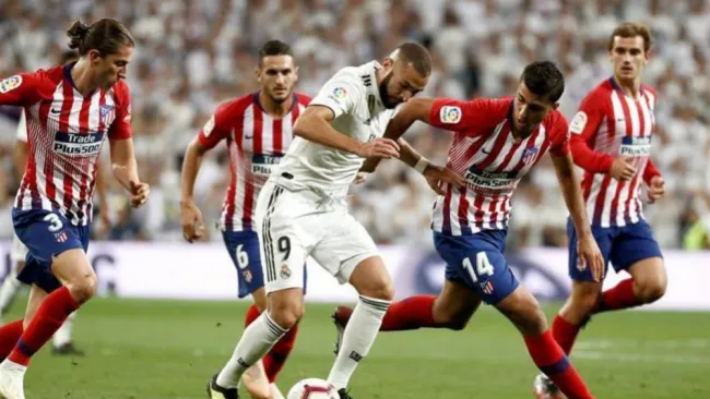 Benzema y jugadores del Atlético de Madrid disputan un balón