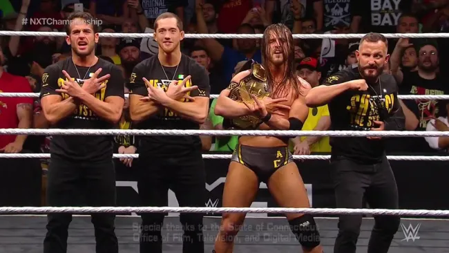 Adam Cole festeja con sus compañeros de The Undisputed Era