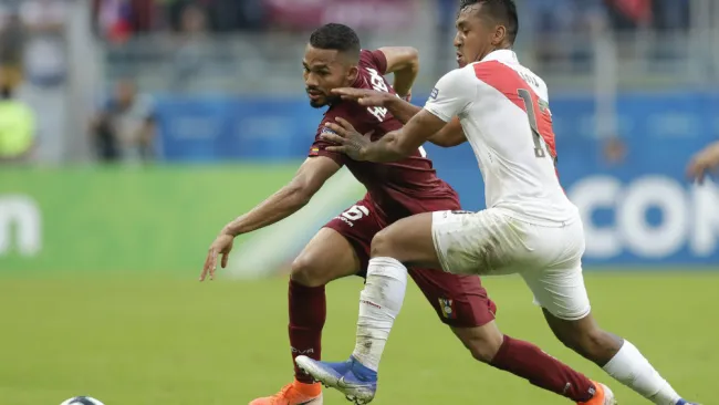 Jugadores de Venezuela y Perú en disputa por el balón 