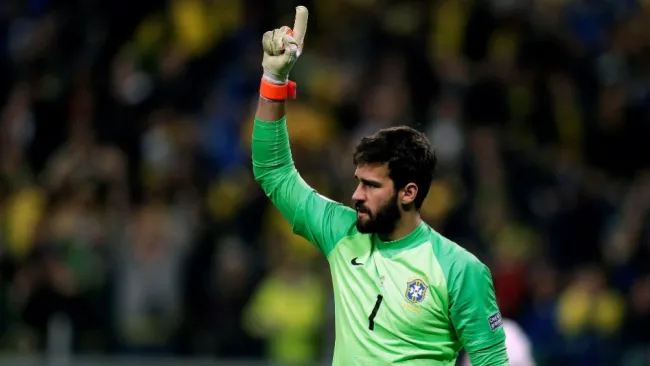 Alisson levanta el brazo en un juego con Brasil