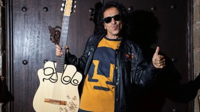 Alex Lora posando con su icónica guitarra y la playera de Pumas
