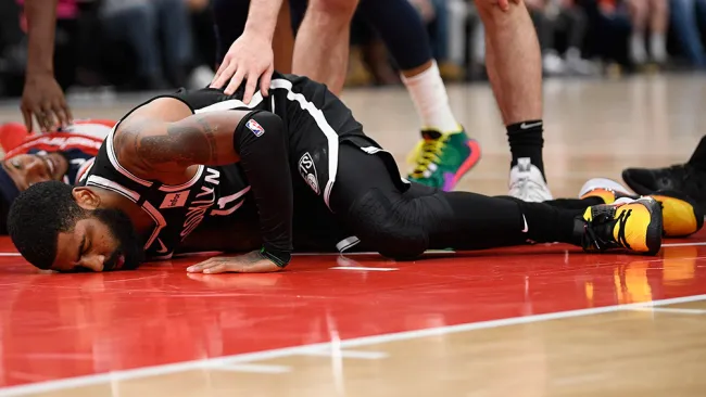 Kyrie Irving, recostado en la duela durante un juego de los Nets