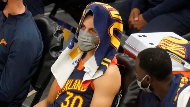 Steph Curry usa cubrebocas en la banca de Warriors