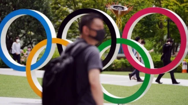 Gente camina junto a los aros olímpicos