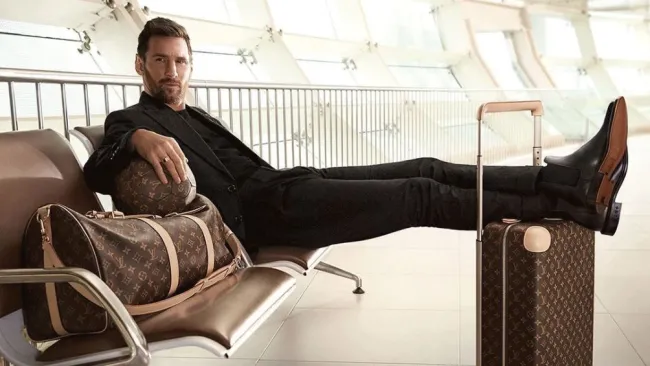 Lionel Messi posando con los pies sobre una maleta Louis Vuitton