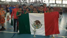 Niños triquis posan con la bandera mexicana y el trofeo de campeón