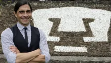 Francisco Palencia posa junto al escudo de Pumas