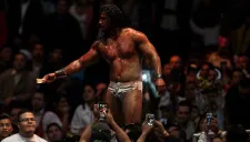 Rush sostiene un billete en la mano