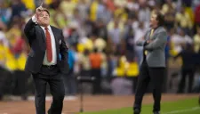 Miguel Herrera al frente da indicaciones mientras La Volpe voltea a ver al público
