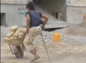 Albañil sin pierna arrastra la carretilla con piedras
