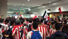 Decenas de aficionados de Chivas esperan la llegada de su equipo en aeropuerto