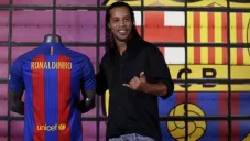 Ronaldinho posa junto a una playera del Barcelona