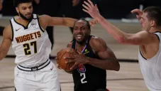 Kawhi Leonard, de los Clippers de Los Ángeles, avanza entre Jamal Murray