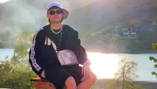 Peso Pluma posa para la foto cerca de un lago