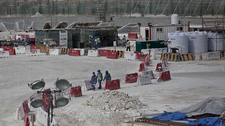 Inmigrantes caminan entre una zona de construcción del estadio Al-Wakra para Qatar 2022