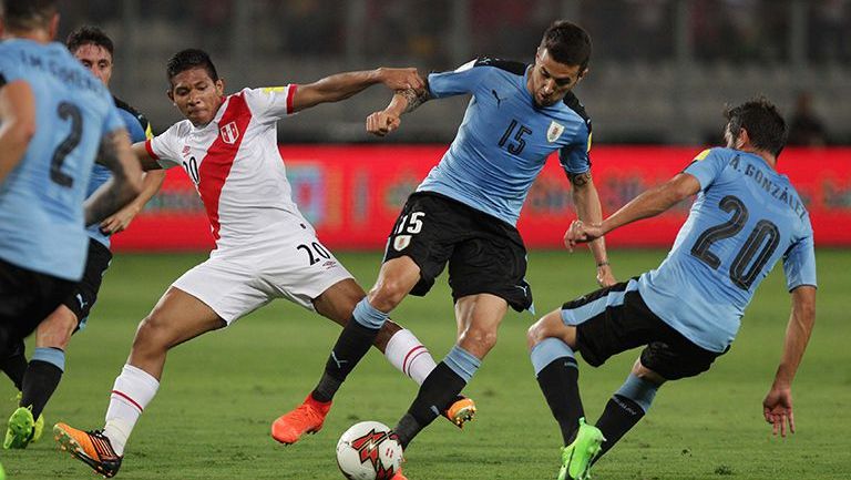 Jugadores de Uruguay y Perú pelean por la posesión del balón