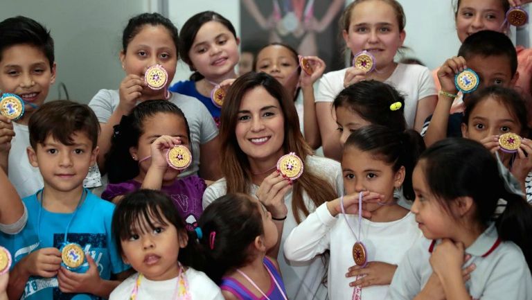 Paola Espinosa presume una medalla junto a un grupo de niños