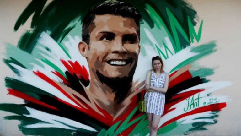 La artista rusa Julia Antipova posa frente al mural que creó de CR7