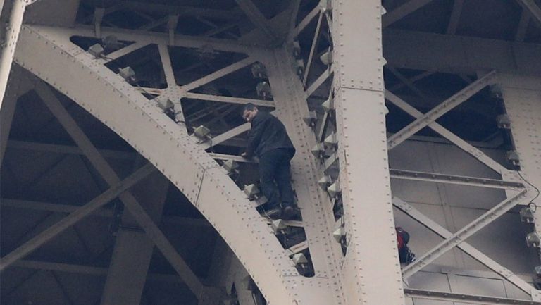 Hombre intentando escalar la torre Eiffel 